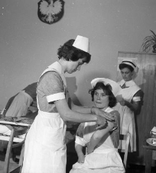 Egzamin pielęgniarski, siostra ze strzykawką przy ramieniu koleżanki, szpital PCK