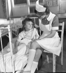 Szpital Wojew&oacute;dzki im. J Śniadeckiego, oddział dziecięcy. Pielęgniarka przy ł&oacute;żku dziewczynki