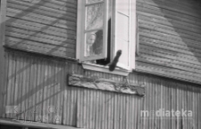 Starsza kobieta wystawiająca miotłe przez okno domu drewnianego, okolice ul. Mazowieckiej, Białystok, druga połowa lat 70. XX w., fot. ze zbiorów Andrzej Trzcińskiego