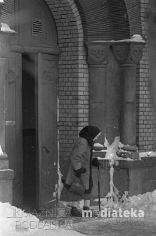 Starsza kobieta przed drzwiami kościoła pw. Św. Wojciecha Biskupa i Męczennika w Białymstoku, ul. Warszawska 46a, Białystok, druga połowa lat 70. XX w., fot. ze zbiorów Andrzeja Trzcińskiego