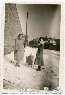 Kobiety z dzieckiem na spacerze przy murze garaży Komendy Milicji Obywatelskiej, ul. Kraszewskiego, Białystok, marzec 1958 r.