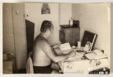 Mężczyzna siedzący w pokoju i notujący coś w zeszycie