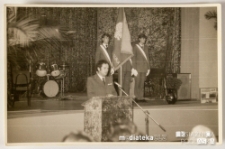 Uroczyste przemówienie, na scenie w tle stoi poczet sztandarowy oraz perkusja, Białystok, Technikum Kolejowe w Starosielcach