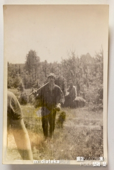 Mężczyźni wychodzący z leśnej polany z narzędziami na barkach