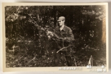 Mężczyzna wynoszący z zarośli ścięte gałęzie