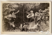 Chłopak siedzący na ogromnym kamieniu w cieniu drzew