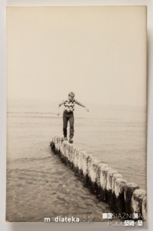 Chłopak chodzący po drewnianych palach na brzegu morza, Ustka, 1979 r.
