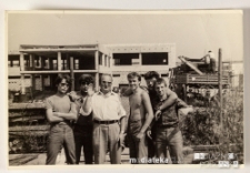 Nastoletni chłopcy z opiekunem na tle szkieletu nowo powstającego budynku