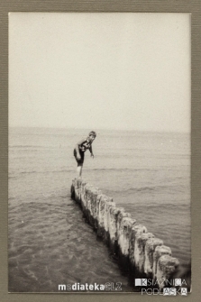 Chłopak chodzący po drewnianych palach na brzegu morza, Ustka, 1979 r.