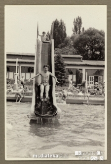 Chłopak wpadający ze zjeżdżalni do odkrytego basenu