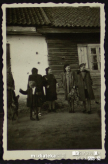 Grupa osób czeka przed domem z kwiatami, Knyszyn, lata 50. XX w.