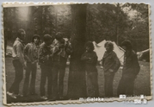 Harcerze stojący w szeregu na tle obozowiska