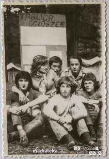 Grupa harcerzy siedząca przed tablicą ogłoszeń, lata 70. XX w.