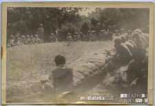 Harcerze siedzący w kręgu w obozie