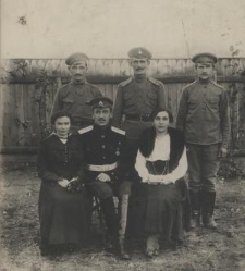 Trzech żołnierzy i jeden oficer w rosyskich mundurach oraz dwie kobiety na tle ogrodzenia