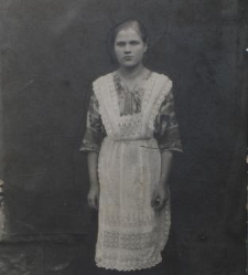 Portret wiejskiej dziewczyny ubranej w kwiecistą bluzkę, ciemną spódnicę, boso
