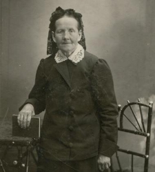 Portret starszej kobiety ubranej w ciemną garsonkę z białym, haftowanym kołnierzem