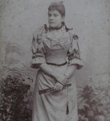 Młoda kobieta w jasnej sukni z wachlarzem w ręku
