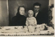 Kobieta i mężczyzna oraz małe dziecko przy trumnie, w której spoczywa kilkuletnia dziewczynka