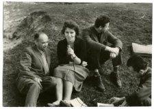 Kobieta z mikrofonem i trzech mężczyzn siedzących na ziemi