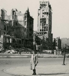 Kobieta stojąca wśród ruin na ul. Napoleona 9 (obecnie Powstańców Warszawy). W tle widok na budynek Prudentialu