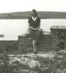 Młoda kobieta siedząca murku przy kościele pw. Niepokalanego Poczęcia nad jeziorem Wigry