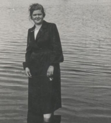 Kobieta w ciemnej sukni stoi w wodzie po kolana