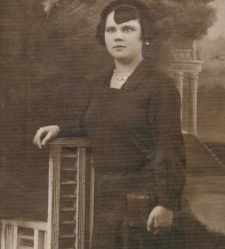 Kobieta w ciemnej sukni stoi przy krześle w atelier fotograficznym