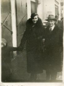 Mężczyzna w kapeluszu oraz kobieta z dzieckiem idący ulicą
